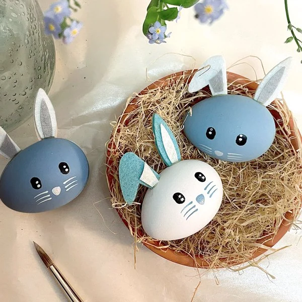 Raffia-wrapped gift box with Easter eggs inside, shown on a table