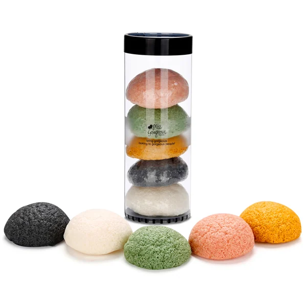 Stack of five colorful konjac facial sponges in a clear tube with loose sponges in front.