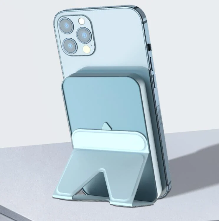 Pale blue magnetic wireless power bank with fold-out kickstand attached to the back of a smartphone