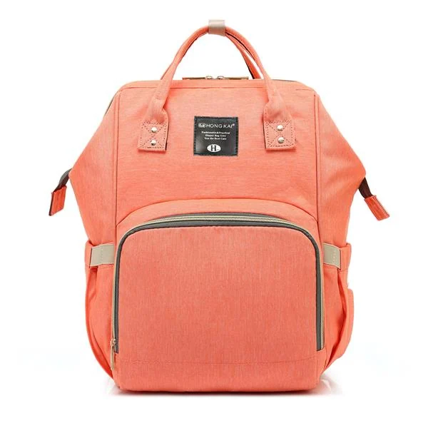Front view of a coral pink multi-function diaper bag backpack with leather trim accents.