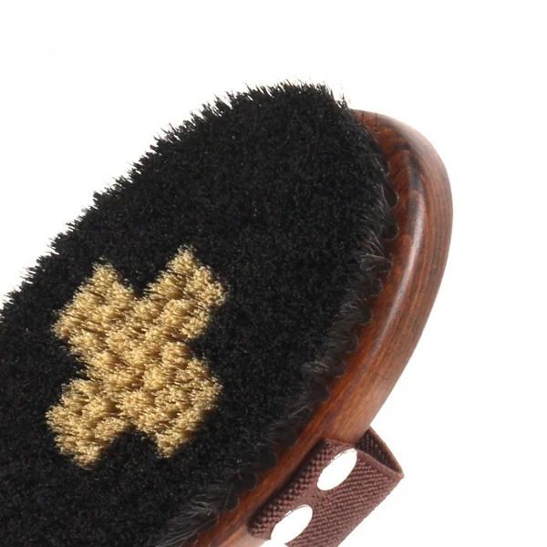 Close-up of a palm grooming brush with black bristles, brown wooden back and elastic hand strap