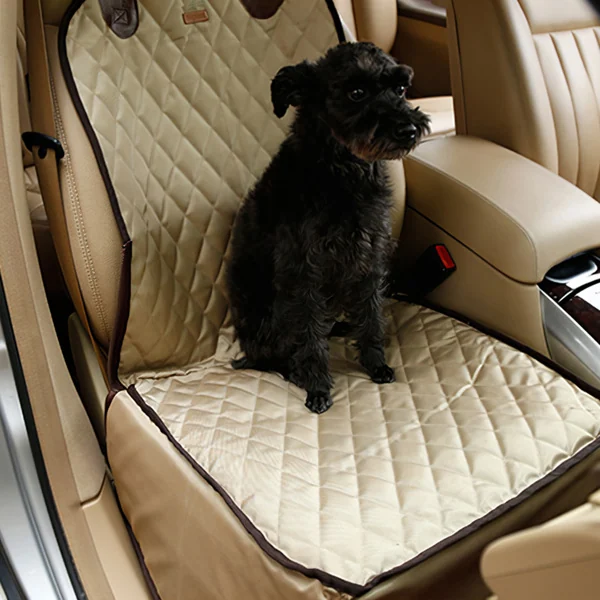 Black dog sitting on a beige quilted hammock seat cover installed in a car interior.