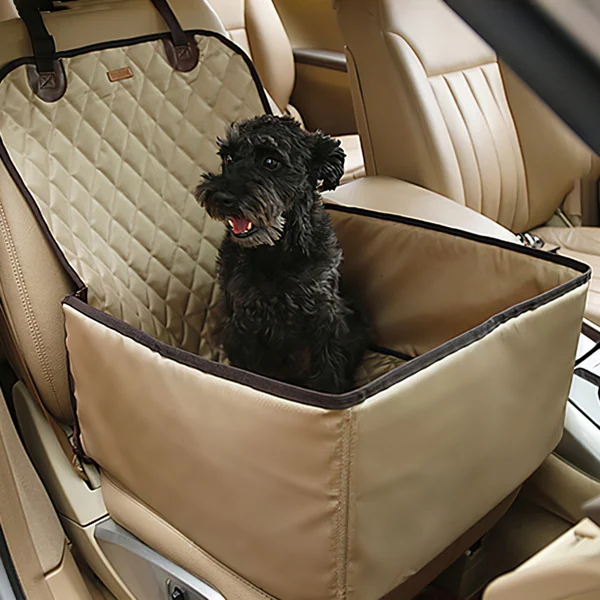 A black dog sits inside a beige, quilted pet car seat cover installed on a vehicle's rear seat.