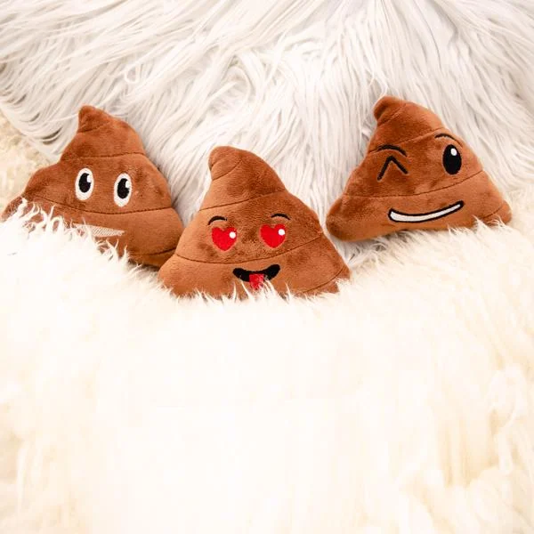 Three brown plush poop emoji dog toys with embroidered smiling faces on a white fluffy blanket