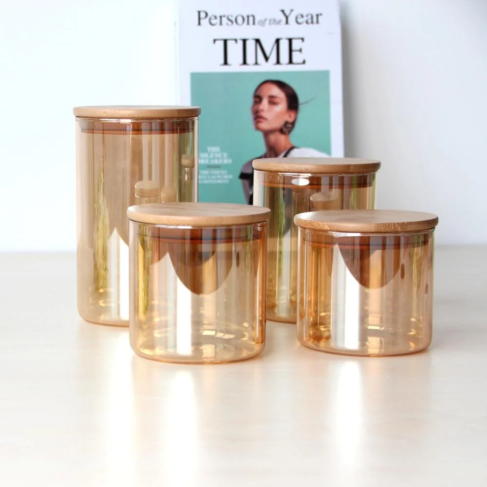 Four amber glass food storage jars with round wooden lids arranged on a light table, a magazine behind them