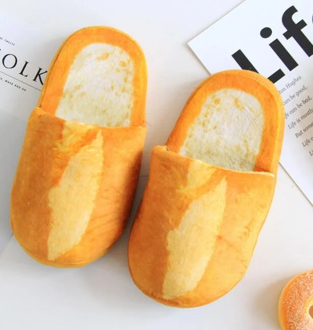 Pair of plush slippers shaped like sliced bread loaves on a white surface with printed paper cards