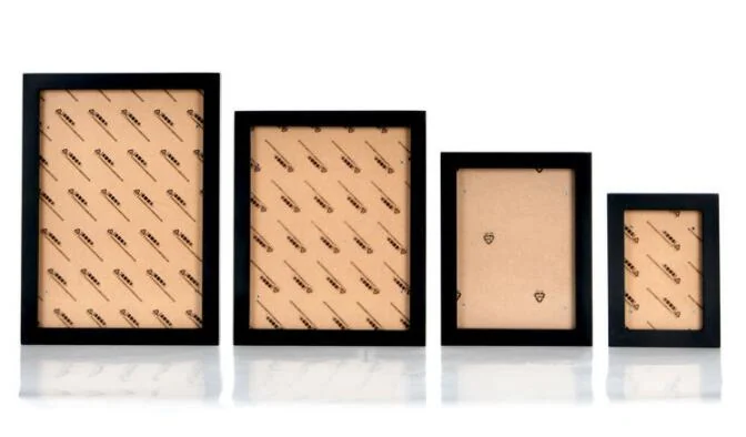 Four black wooden photo frames in descending sizes standing on a white reflective background, showing blank backing boards.