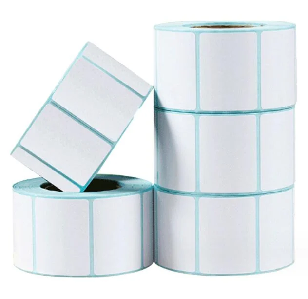 Stacked rolls of blank white thermal transfer labels with light blue liner, one roll tilted on top