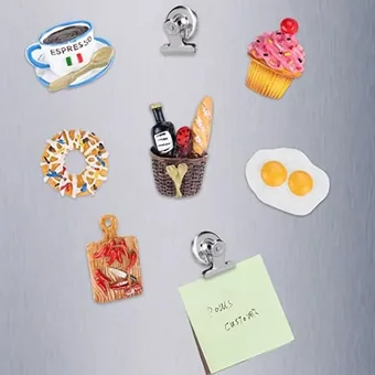 Assorted 3D resin food fridge magnets, including espresso cup, cupcake, donut, wine basket, and fried egg, on a stainless steel surface