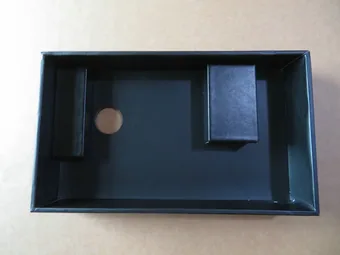 Black PU tray insert with molded compartments and a circular cutout, lying on a beige surface.