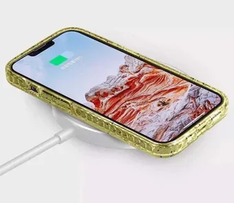 Recycled material phone case in gold speckled finish shown on a smartphone while charging on a white wireless pad.