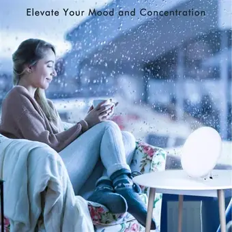 Woman relaxing by a rainy window with a light therapy lamp glowing on a side table