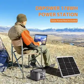A man uses a laptop on a portable power station and solar panel while camping on a scenic mountain ridge.