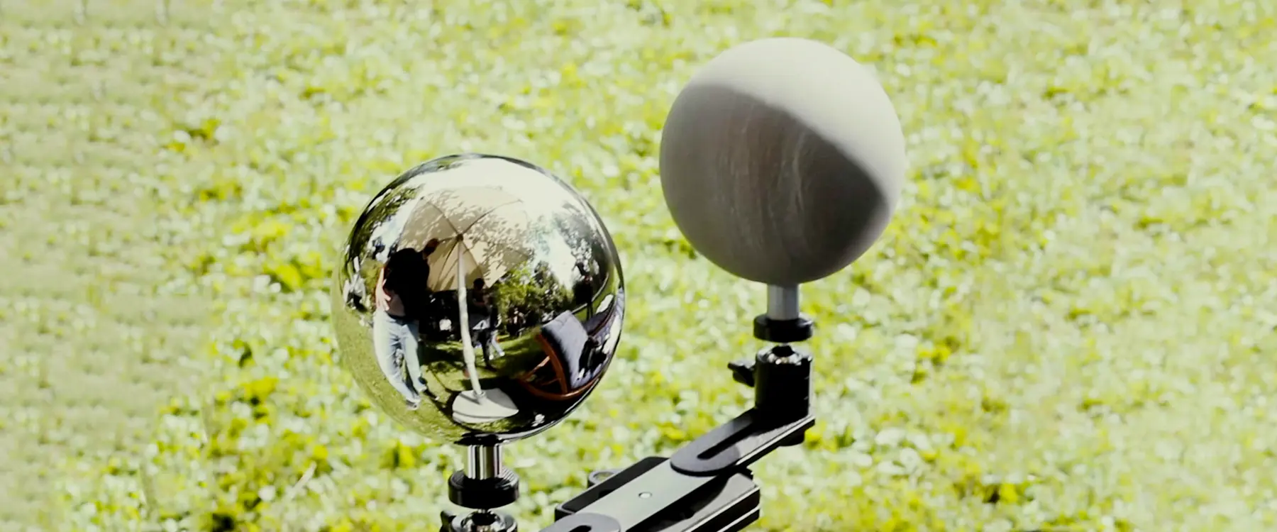 Chrome ball and 18 percent grey ball mounted side by side on a handle outdoors