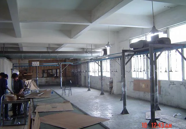 Overhead conveyor carrying steel furniture frames through the coating line