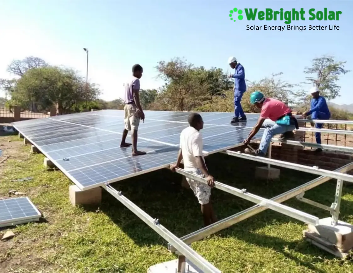 Five men installing solar panels onto a metal mounting frame outdoors.