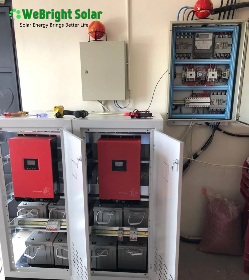 Open electrical cabinets containing red solar inverters and battery banks mounted on a wall.