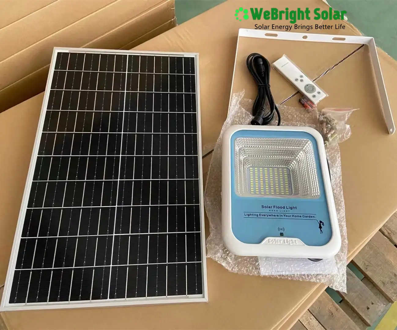 A solar panel and a solar-powered flood light with a remote and mounting bracket.