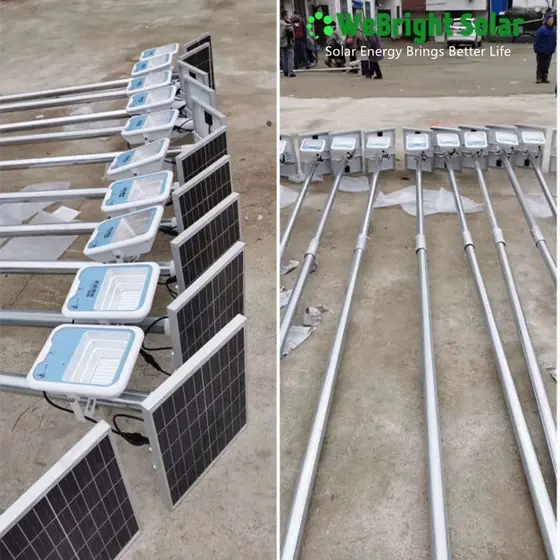Rows of solar LED street lights with panels and mounting poles laid out on a concrete floor.