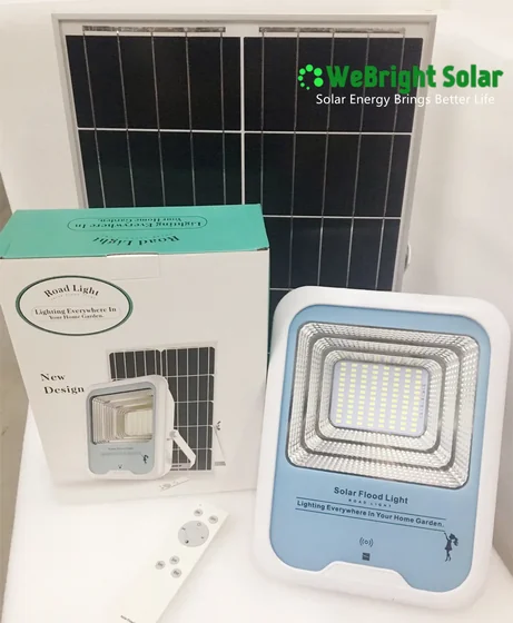 A solar LED flood light with a separate solar panel, product packaging box, and a small remote control.