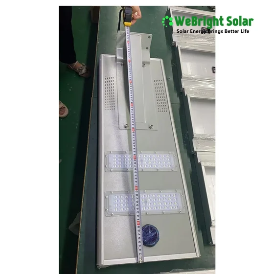 Person measuring the length of a solar LED street light fixture with a tape measure.