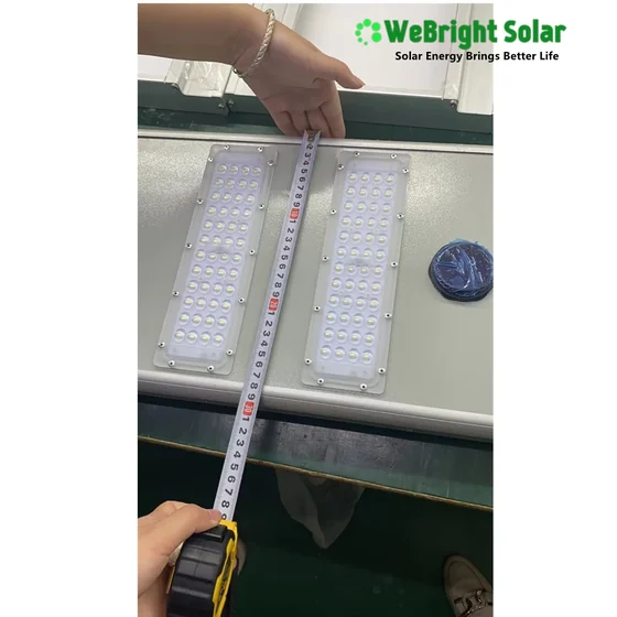 Two rectangular LED solar light panels are being measured on a table with a tape measure.