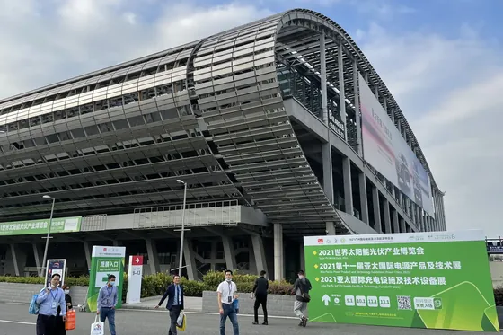 Large modern convention center exterior with people walking and a green sign listing solar industry events in Chinese.