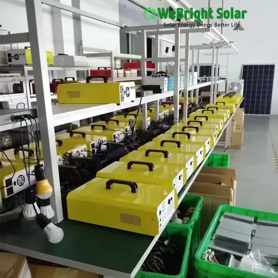 Rows of yellow portable solar power units with black handles lined up on workbenches in a factory.