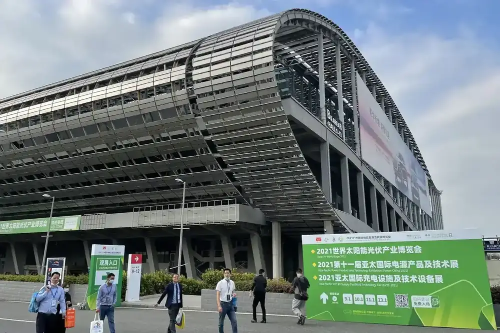 Large modern convention center exterior with people walking and a green sign listing solar industry events in Chinese.