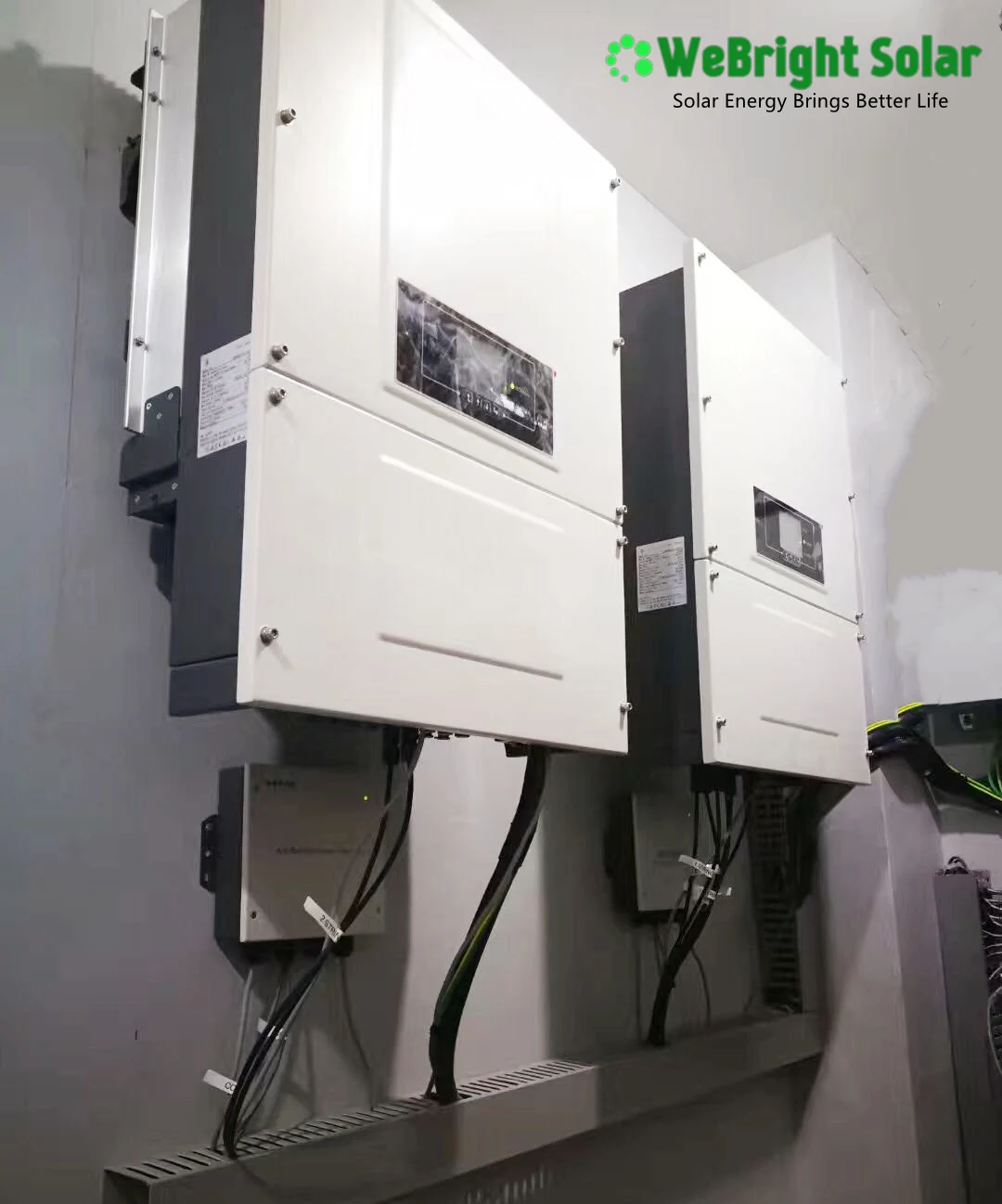 Two large white industrial inverters mounted on a wall with cabling