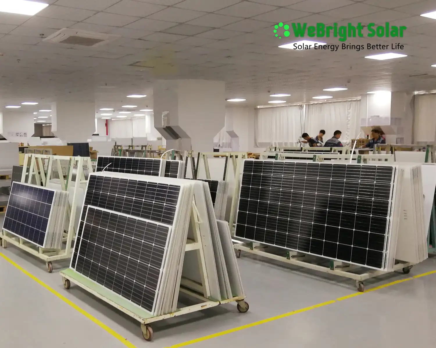 Solar panels on wheeled carts inside a factory assembly room.