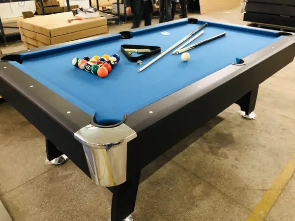 A completed pool table with blue cloth chrome corner castings pockets balls and cues laid out for a play check