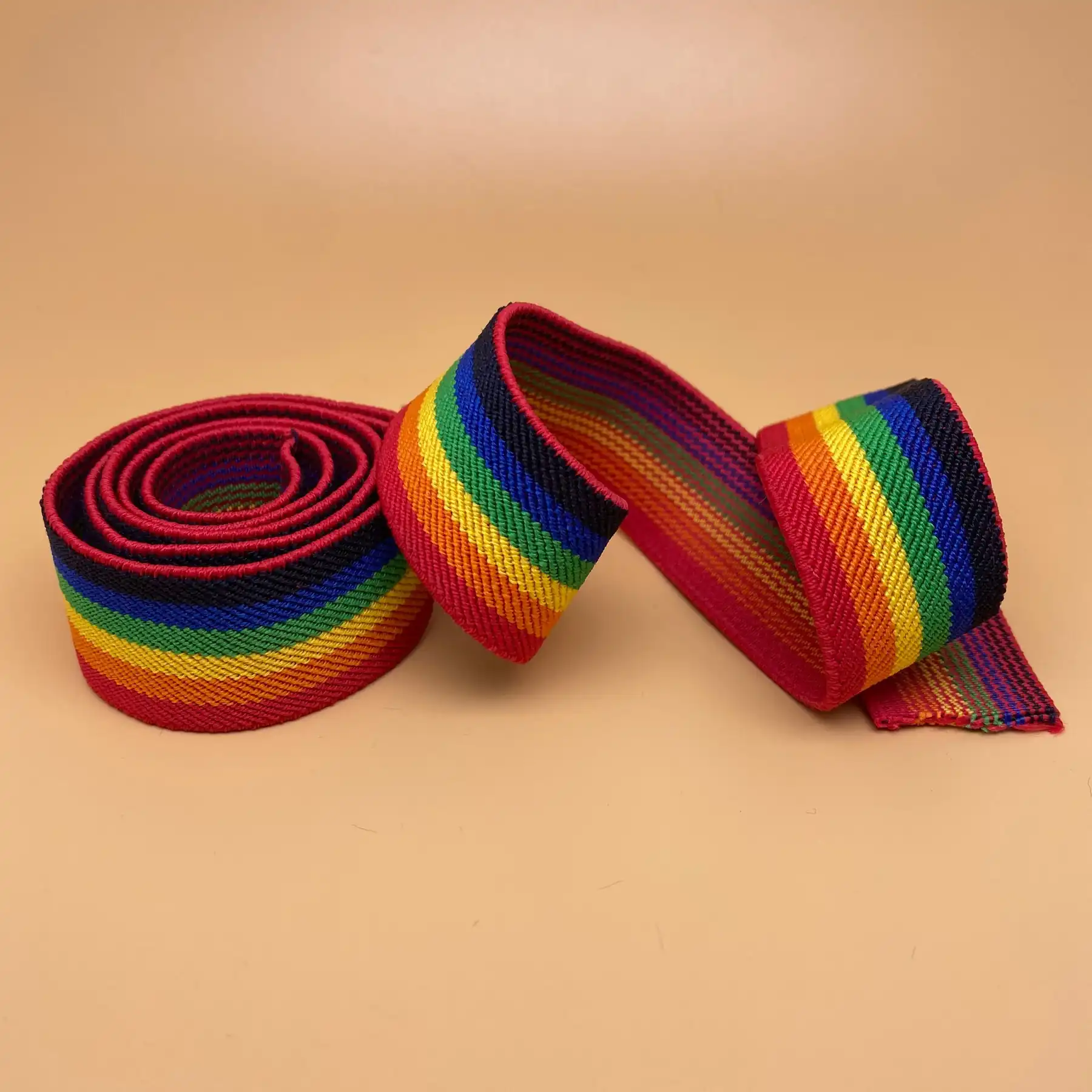 Rainbow striped woven webbing tape coiled on a warm background