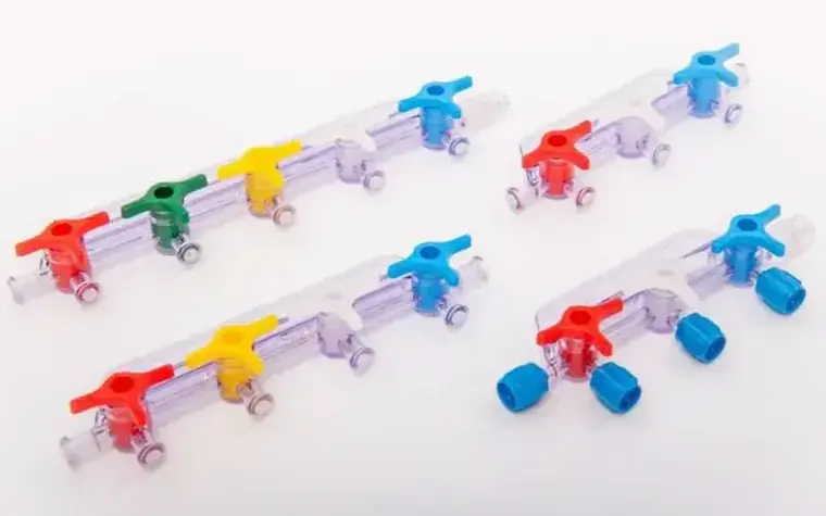 Transparent moulded stopcock assemblies with coloured handles laid out in rows