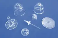 Transparent moulded components and caps photographed against a blue background