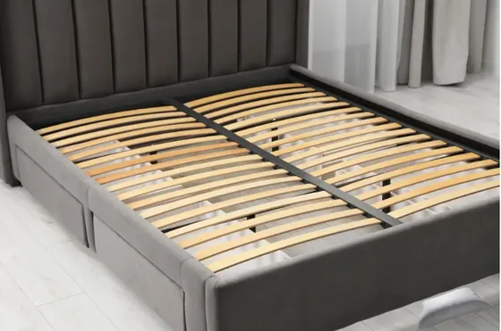 Cambered wooden bed slats installed across an upholstered bed frame