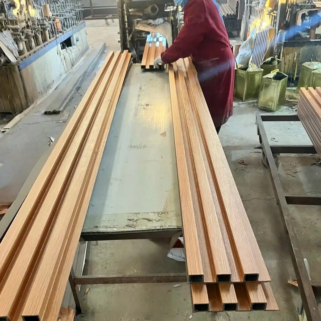 Factory worker handling extruded WPC cladding boards with an embossed wood grain surface