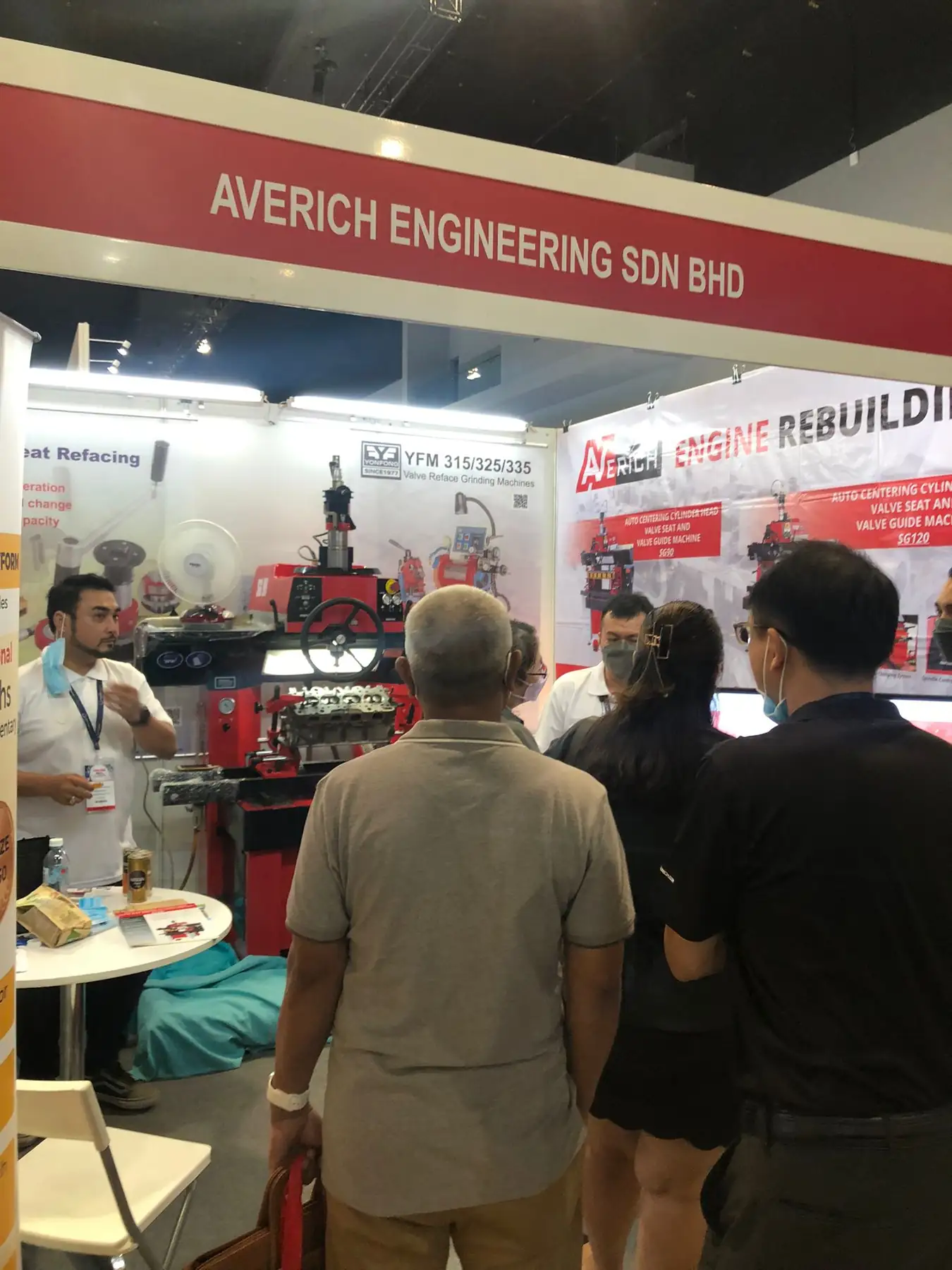 Visitors at the exhibition stand looking at engine rebuilding and valve refacing equipment on display