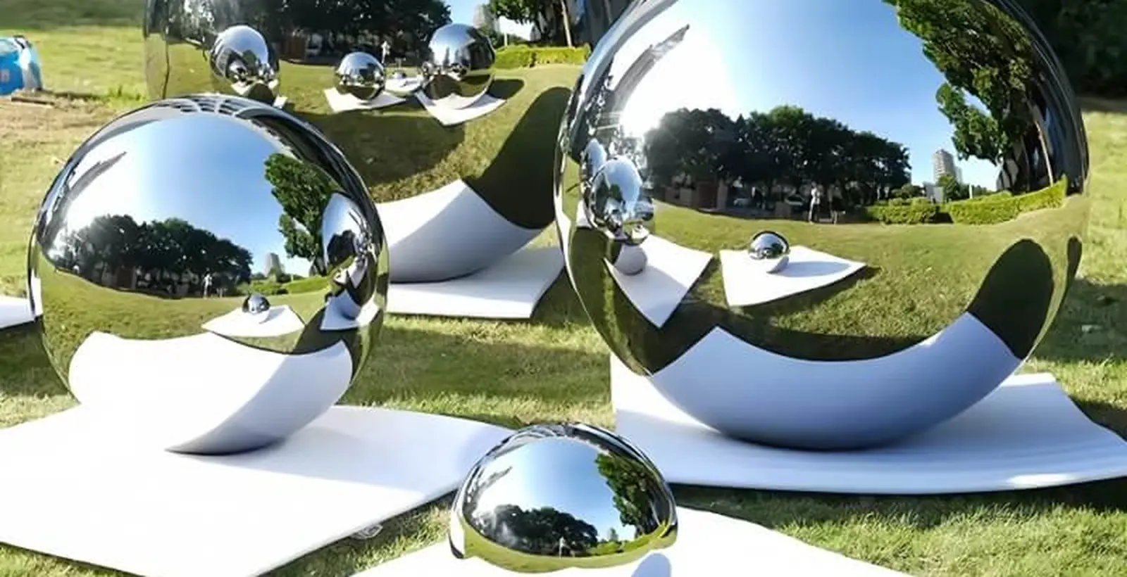 Group of mirror polished stainless steel spheres and a hemisphere arranged on a lawn