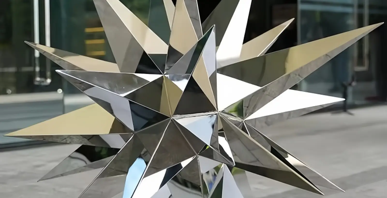Faceted stainless steel starburst sculpture installed at a glazed building entrance