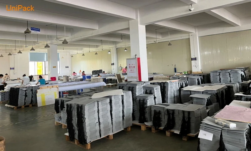 Stacks of cut and printed paper bag blanks staged on pallets in the workshop