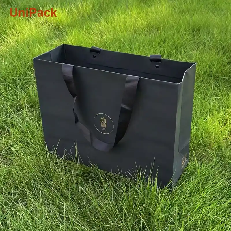 Black dyed paper shopping bag with foil stamped logo and rope handles