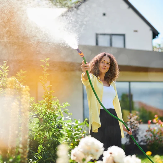 Gardener watering a flower bed with a hose and quick connector