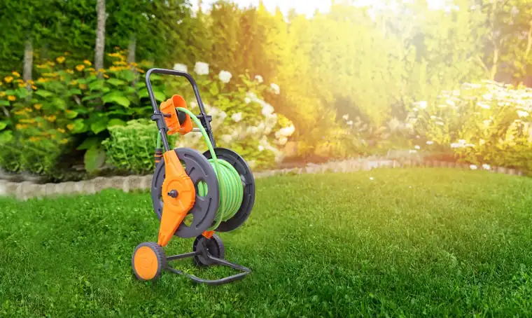 Garden hose cart and watering equipment on a sunlit lawn