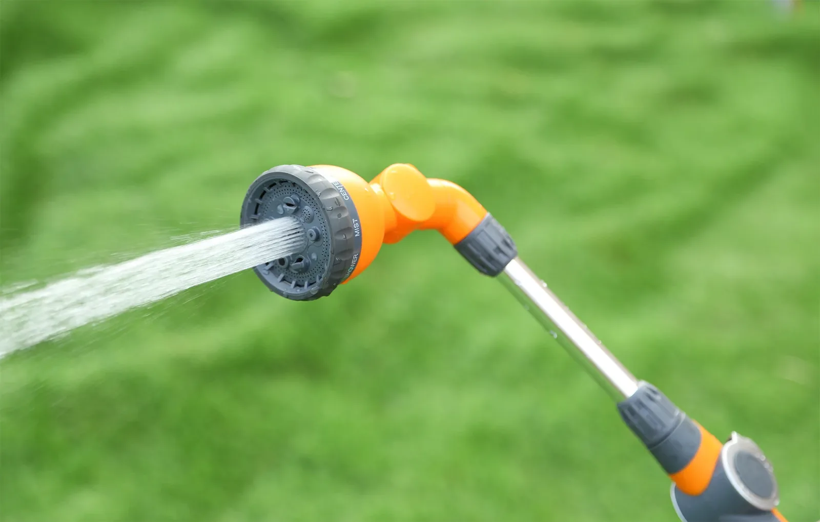 Close view of a YIMAY spray gun watering a green lawn