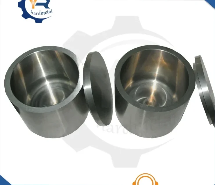 Two polished cylindrical metal grinding jars with flat lids on a white background
