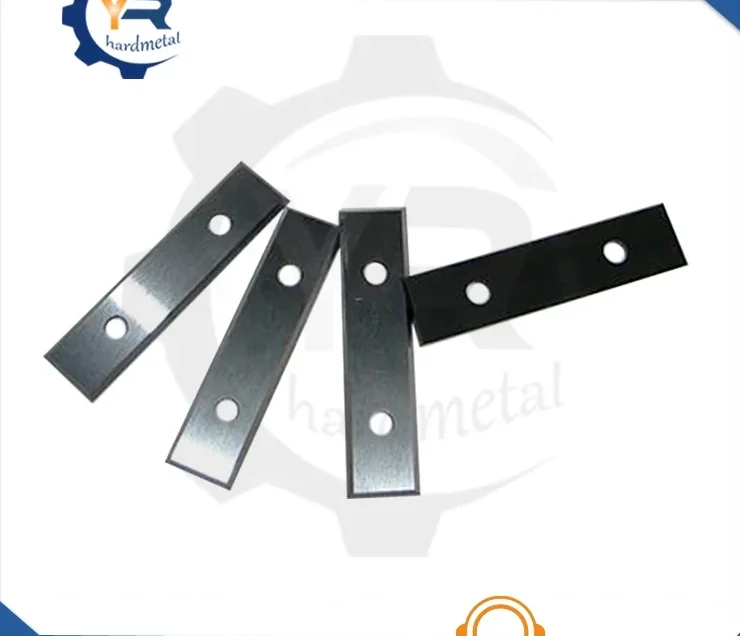 Four rectangular tungsten carbide inserts with two mounting holes each, fanned on a white background