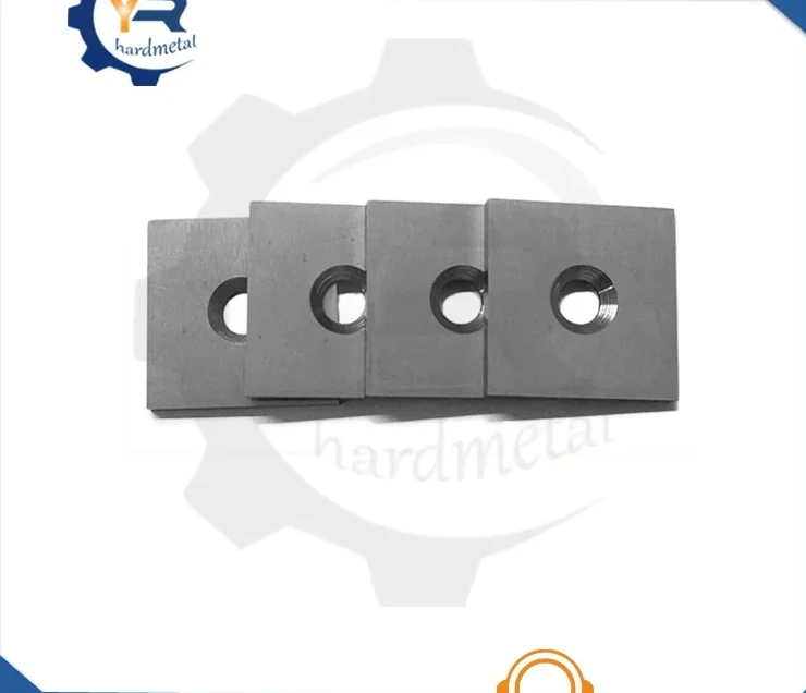 Four square tungsten carbide inserts with center holes lined up on a white background