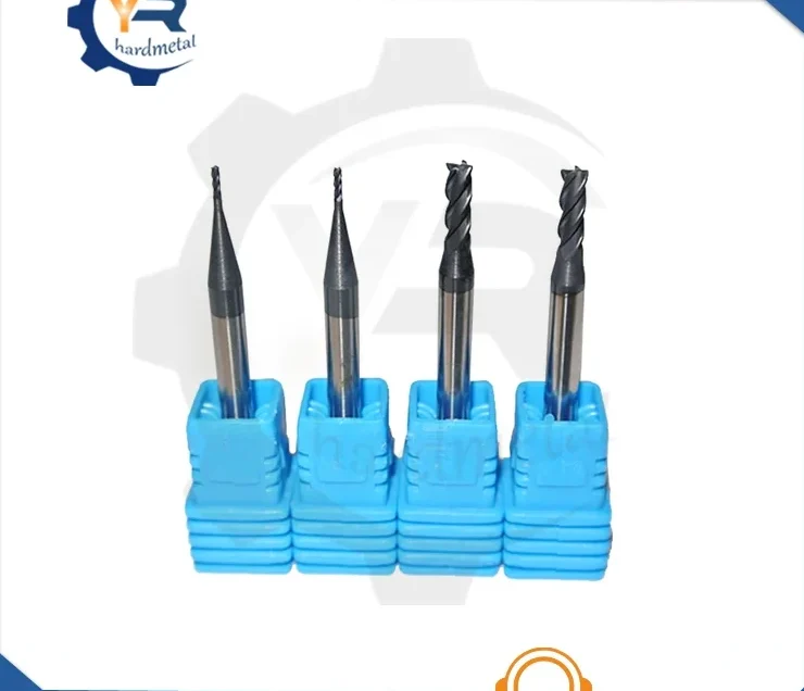Four carbide end mills with flute and ball-nose tips standing upright in blue plastic holders
