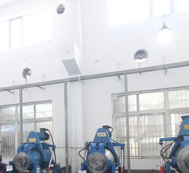 Bright factory workshop with blue industrial machines along the wall and ventilation fans mounted high on white walls